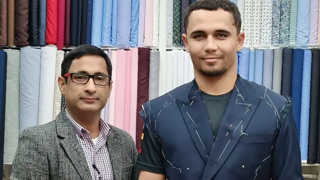 Client wearing a basted navy double-breasted jacket marked with chalk during a first fitting