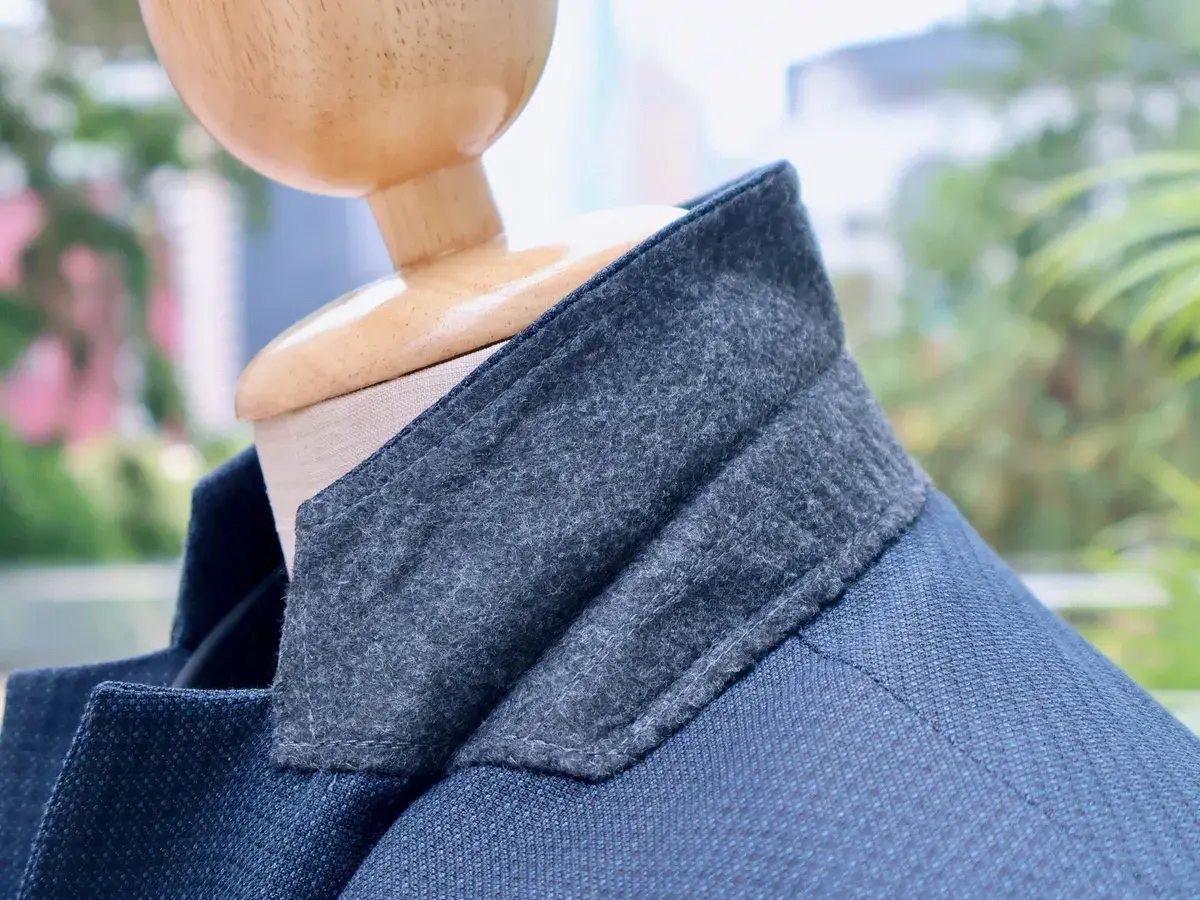Textured blue bespoke jacket with a grey felt under-collar on a mannequin