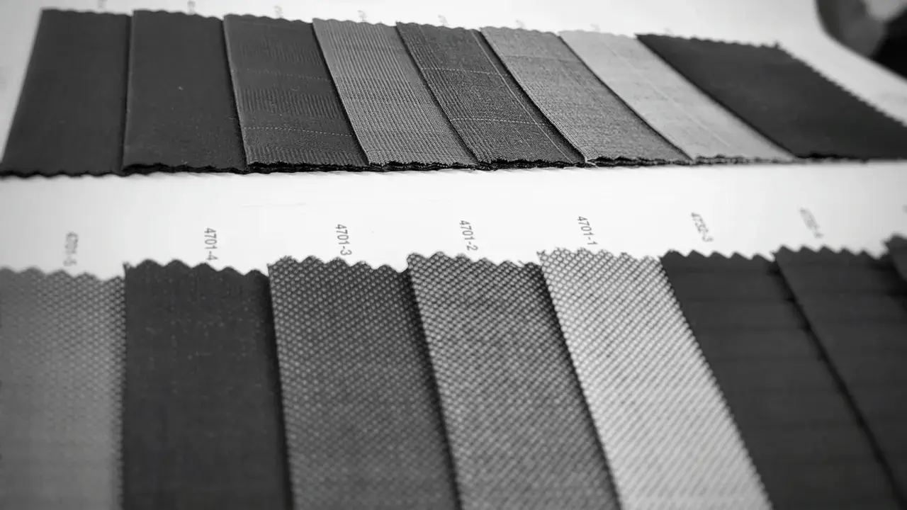 Black-and-white photo of dark suiting fabric swatches laid out in rows