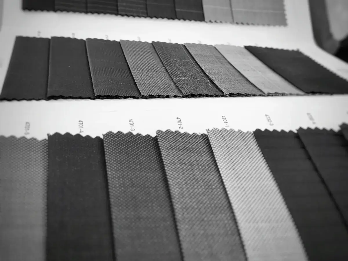 Black-and-white photo of dark suiting fabric swatches laid out in rows