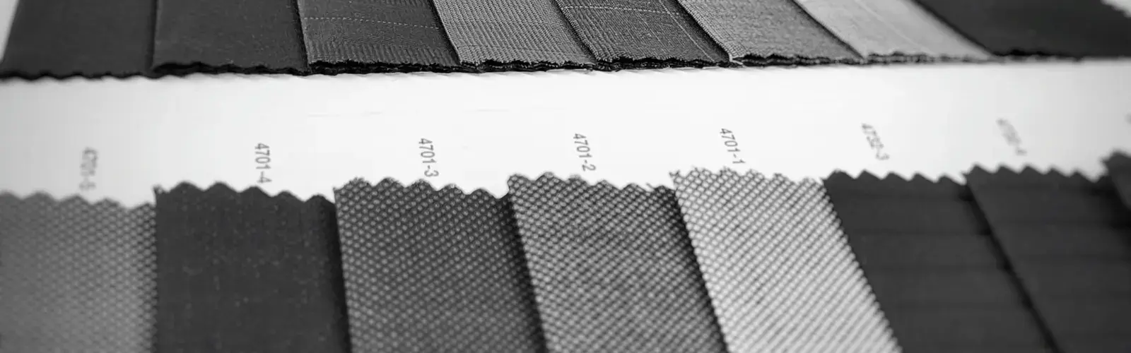 Black-and-white photo of dark suiting fabric swatches laid out in rows