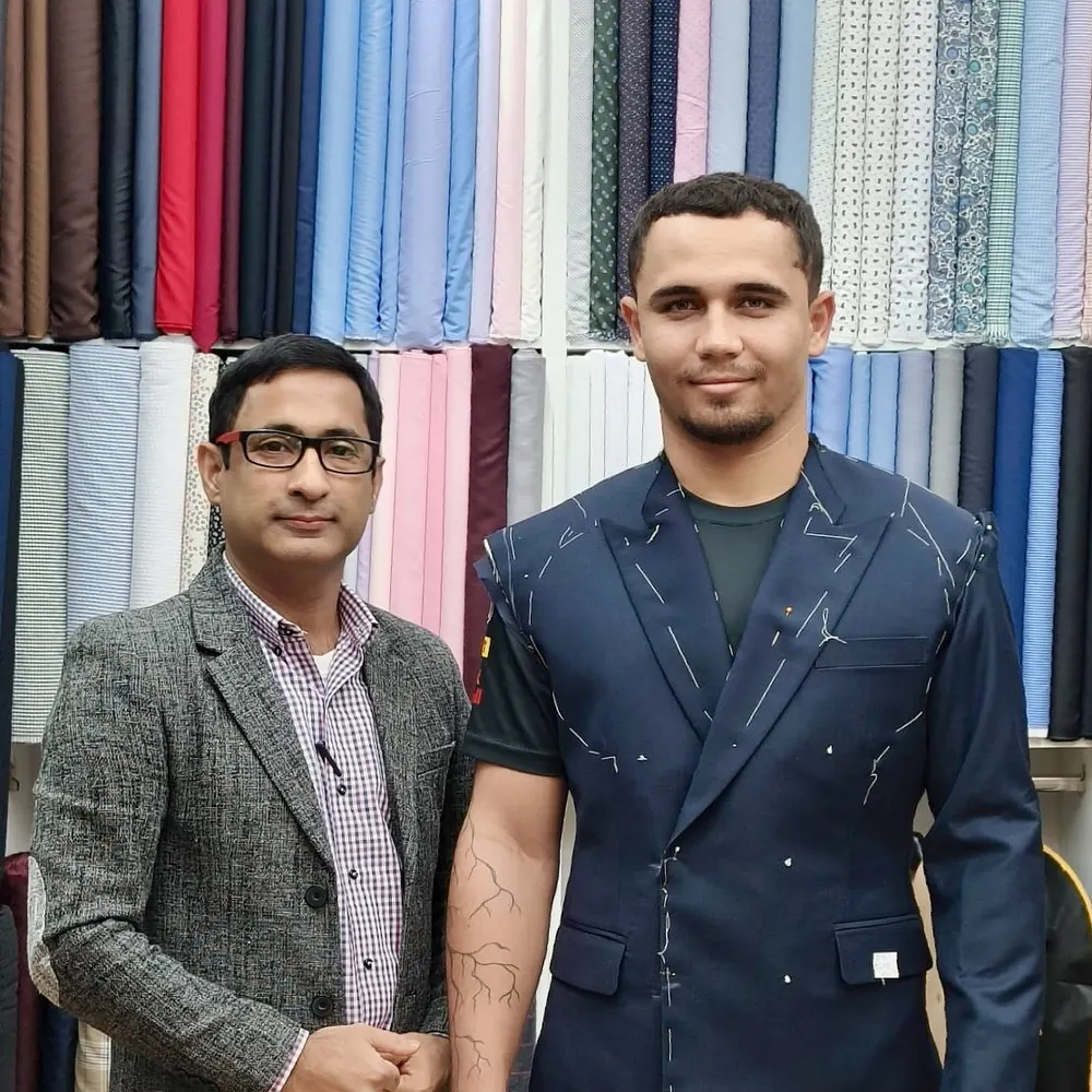 Client wearing a basted navy double-breasted jacket marked with chalk during a first fitting