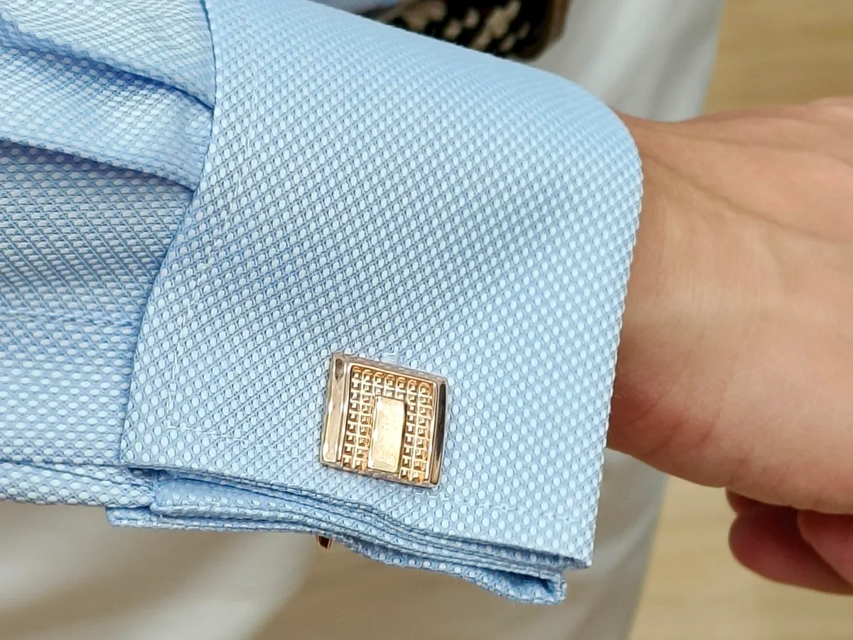 Light blue textured shirt cuff fastened with a gold cufflink