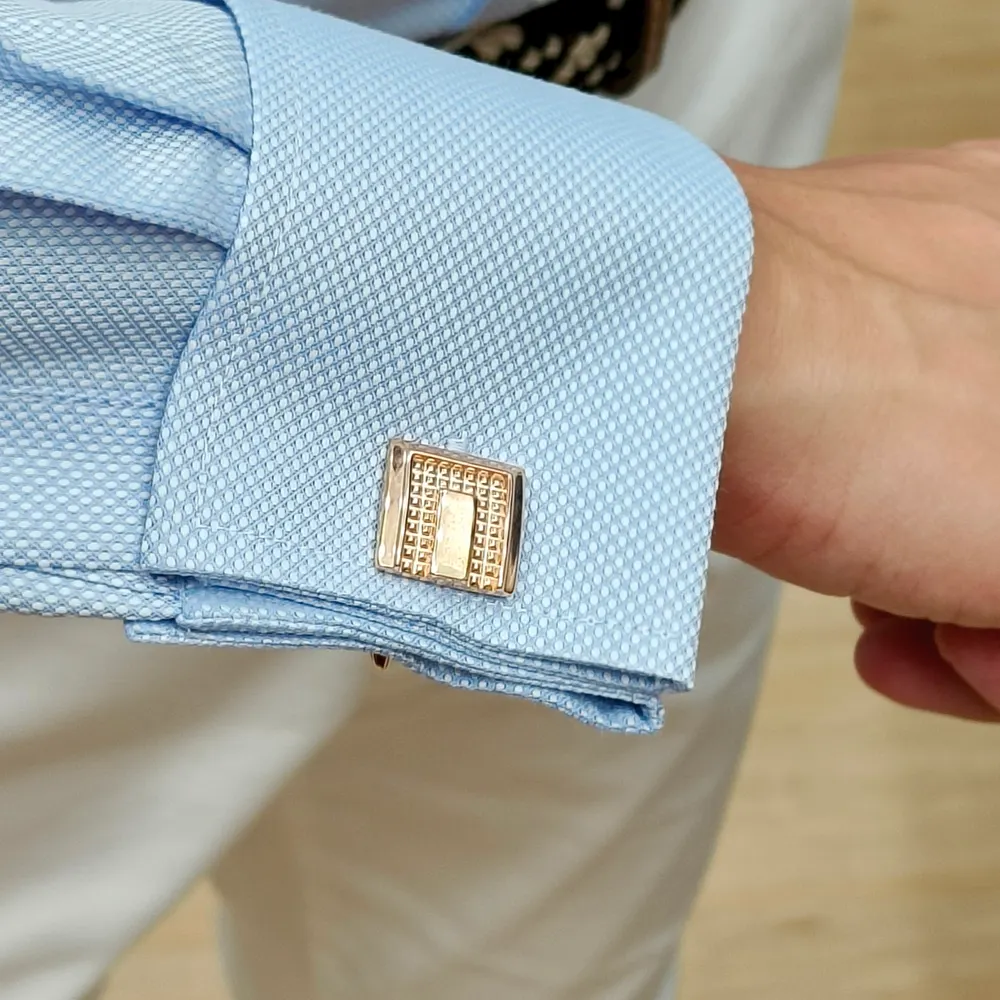 Light blue textured shirt cuff fastened with a gold cufflink