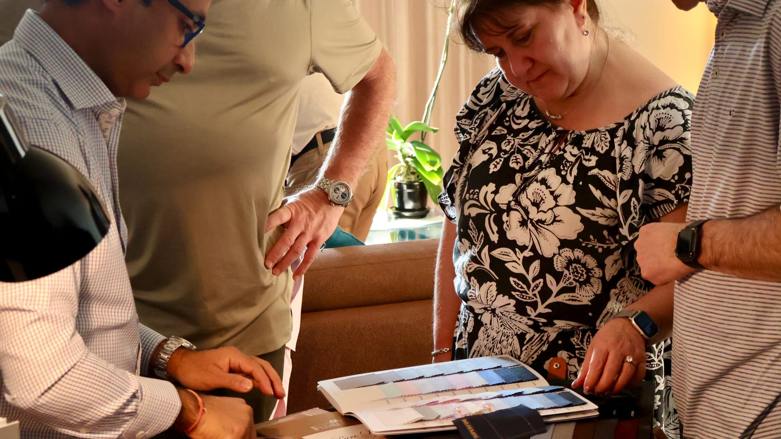 Customers and tailors looking through fabric swatch books together during a consultation