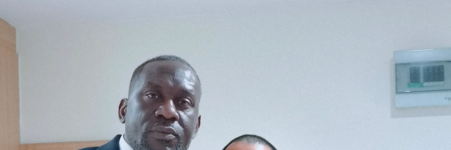 Client in a navy three-piece suit posing with a tailor after a fitting