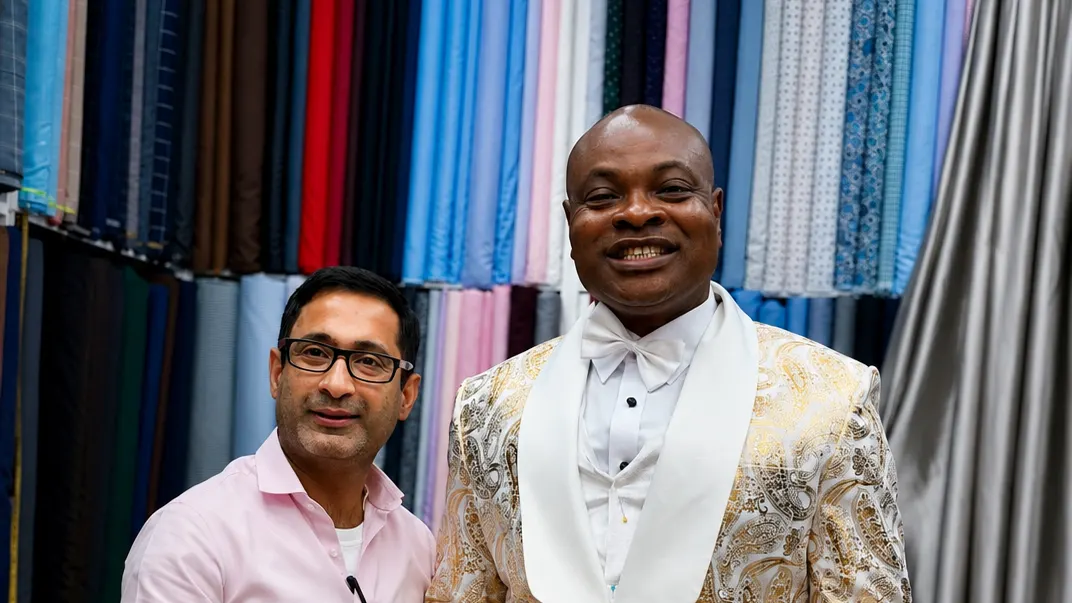Client in a gold paisley dinner jacket with a white shawl collar and bow tie beside a tailor