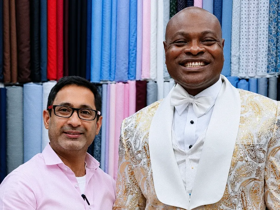 Client in a gold paisley dinner jacket with a white shawl collar next to a tailor in a pink shirt
