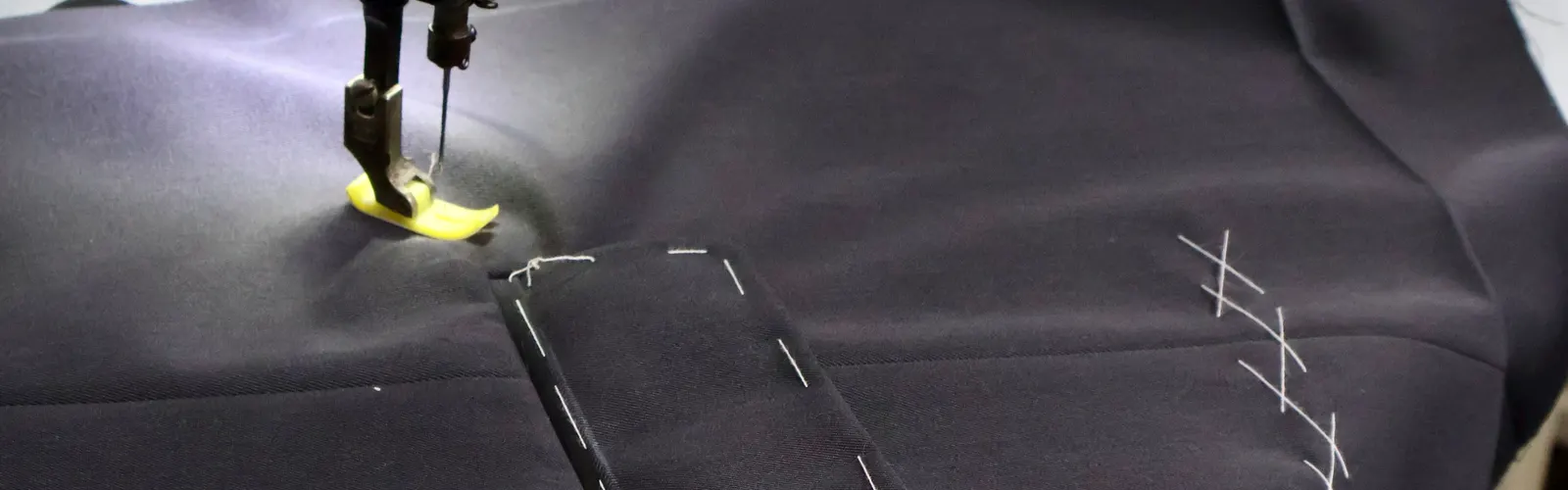 Sewing machine stitching a welt pocket on navy suit cloth with basting marks