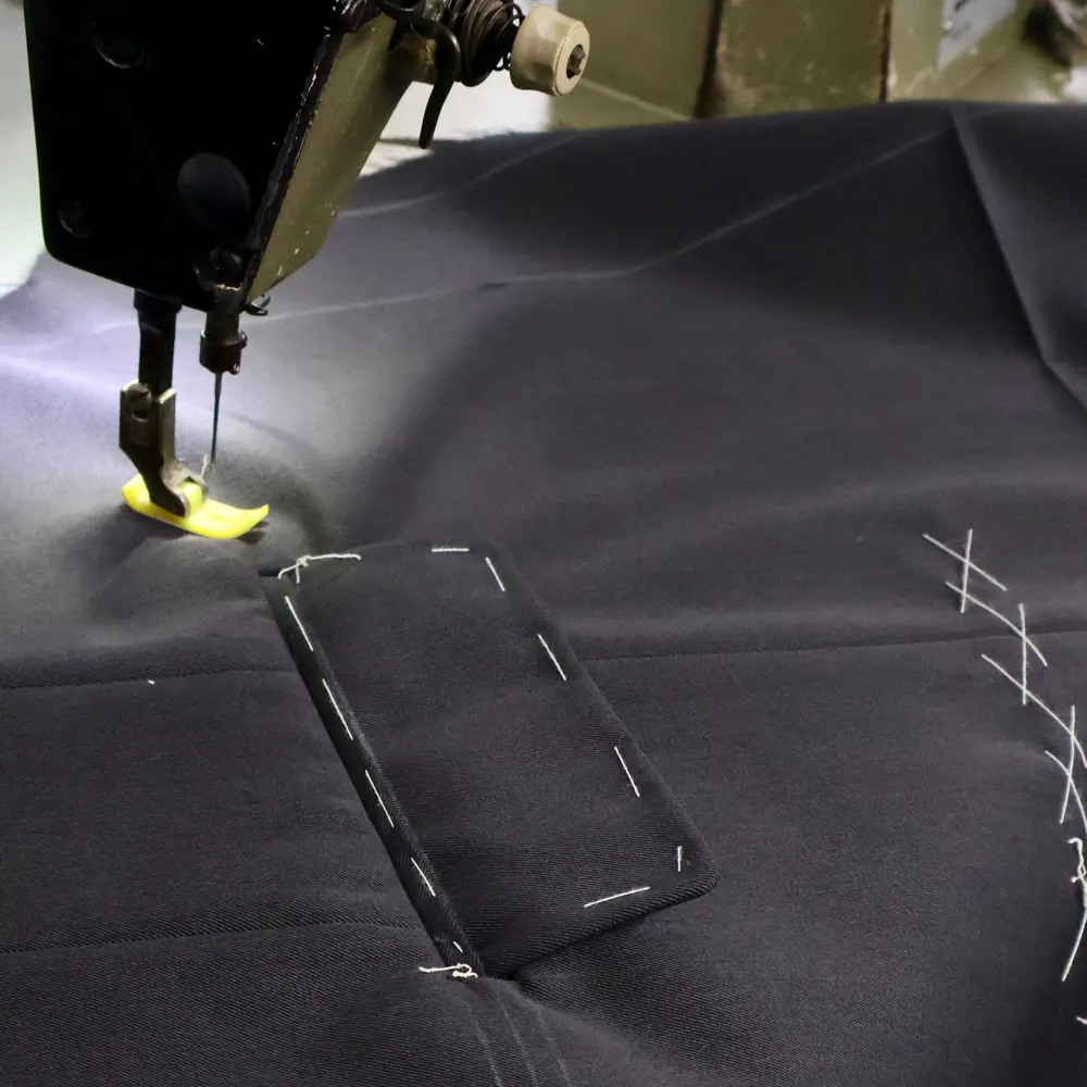 Sewing machine stitching a welt pocket on navy suit cloth with basting marks