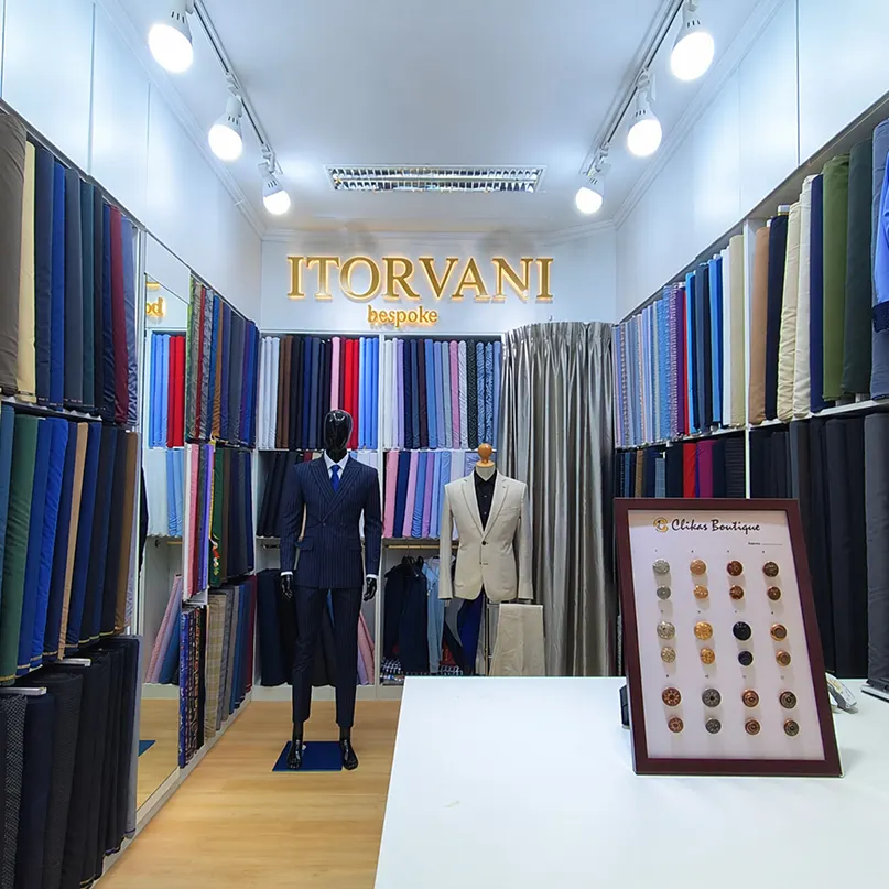 Inside the ITORVANI bespoke tailor shop at Platinum Fashion Mall, with fabric rolls, suit mannequins and the illuminated ITORVANI sign