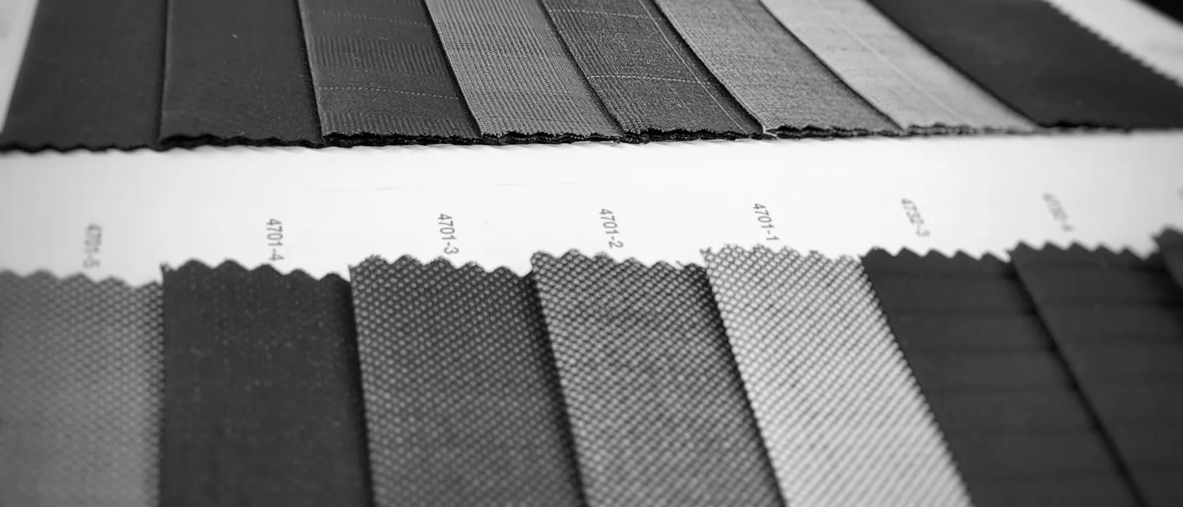 Black-and-white photo of dark suiting fabric swatches laid out in rows