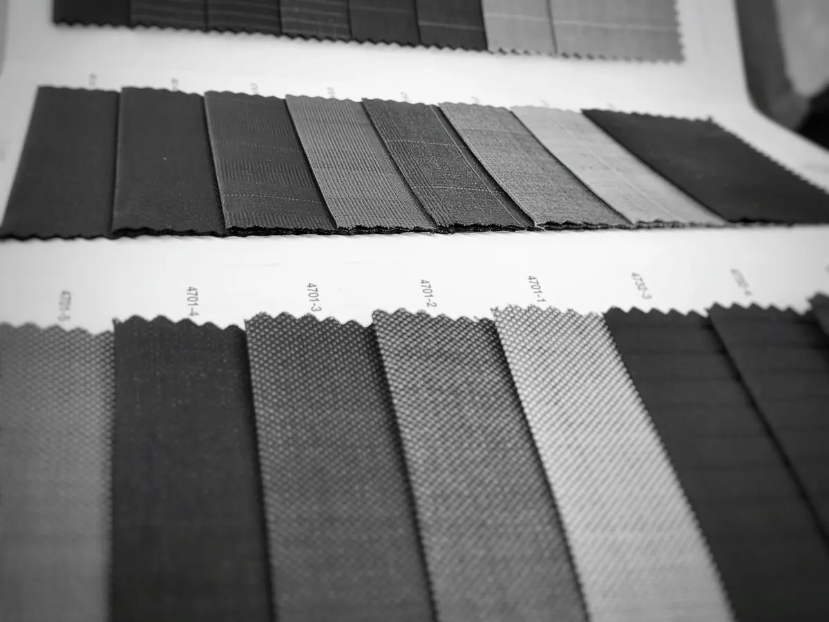 Black-and-white photo of dark suiting fabric swatches laid out in rows