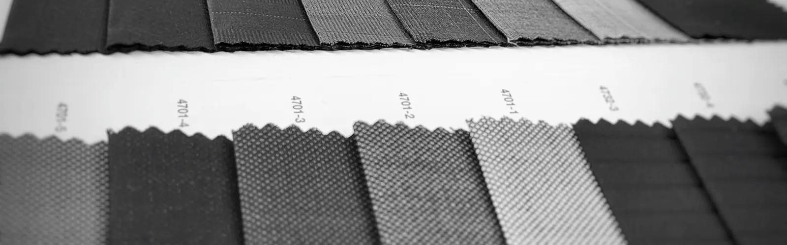Black-and-white photo of dark suiting fabric swatches laid out in rows