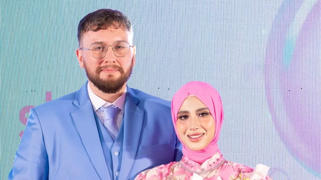 Groom in a light blue three-piece suit holding a bouquet beside his bride