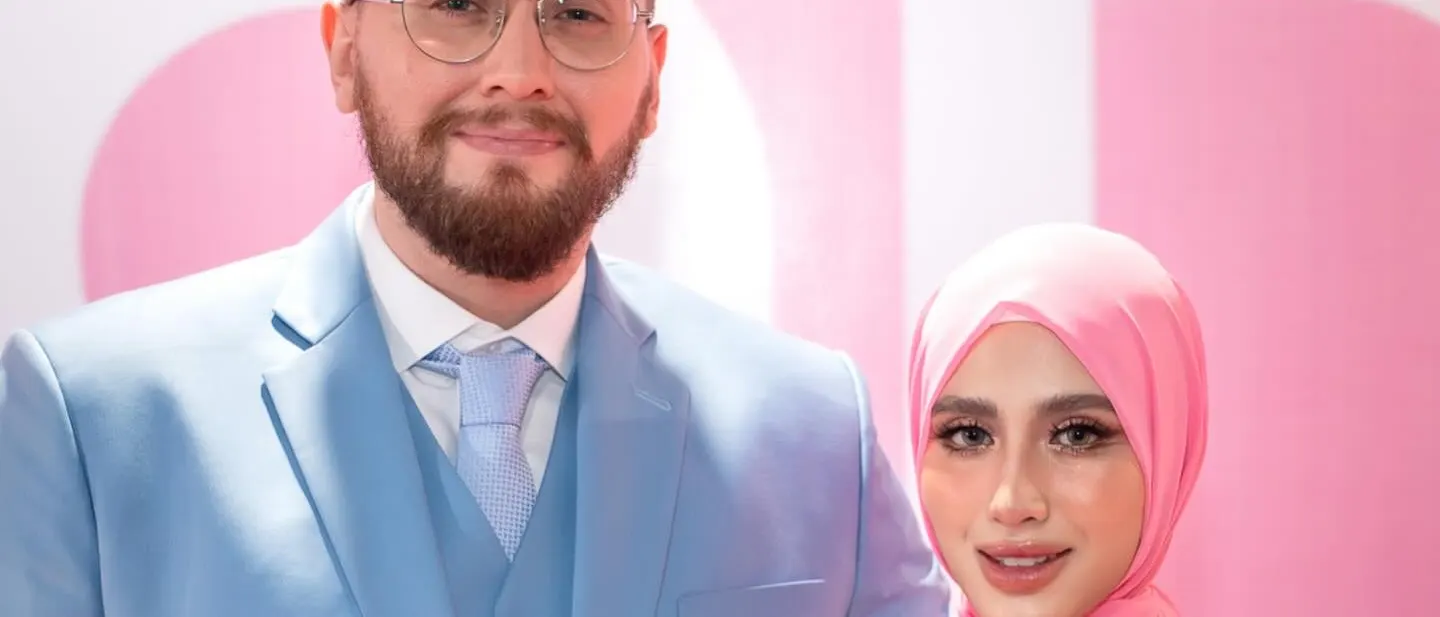 Groom in a light blue three-piece suit with his bride in a pink floral outfit