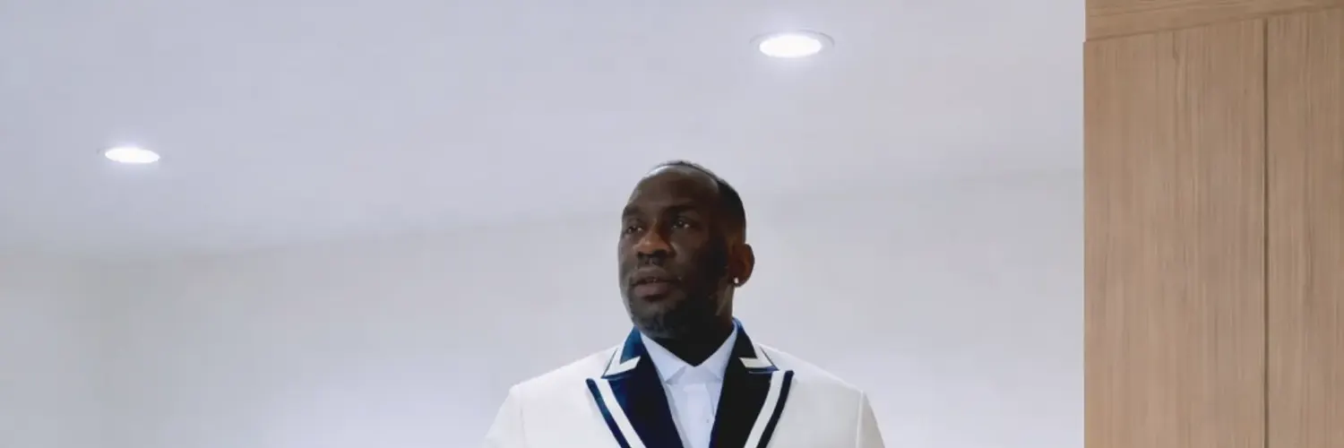 Client in a white double-breasted tuxedo jacket with navy trim buttoning the jacket
