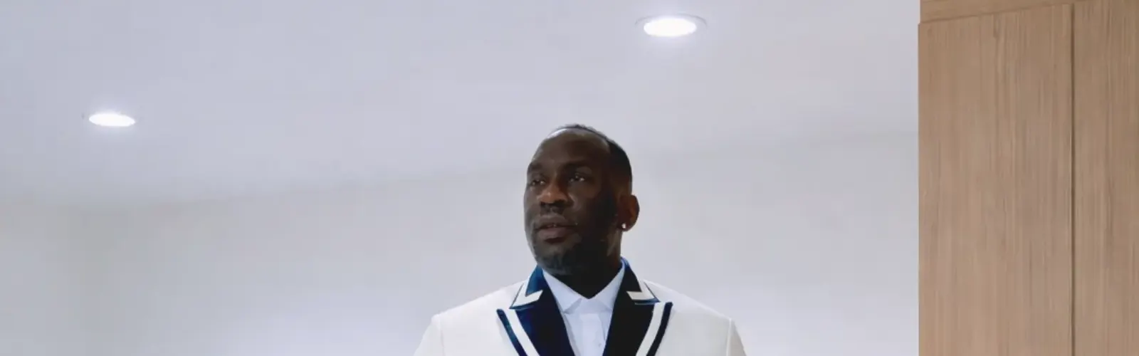 Client in a white double-breasted tuxedo jacket with navy trim buttoning the jacket