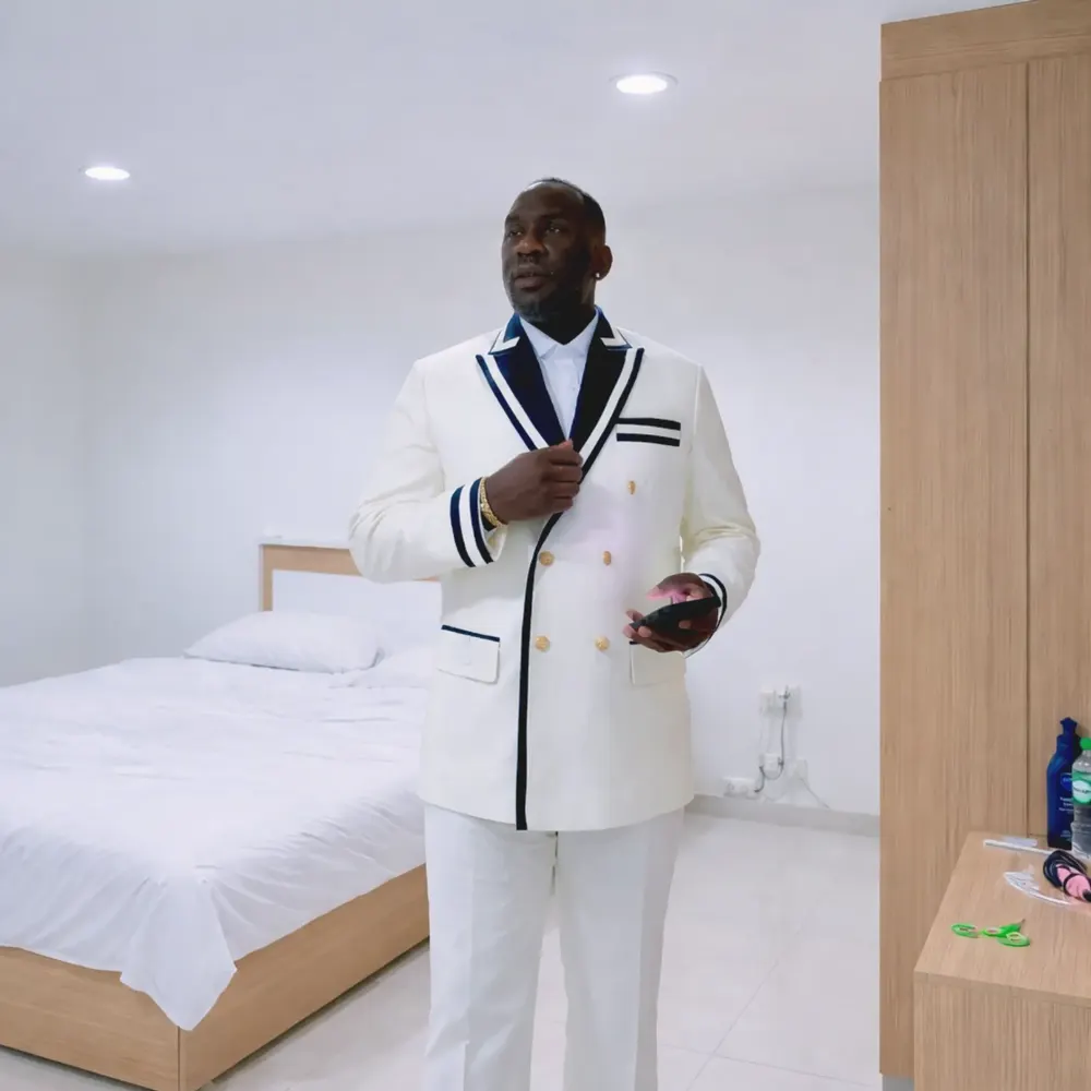 Client in a white double-breasted tuxedo jacket with navy trim buttoning the jacket