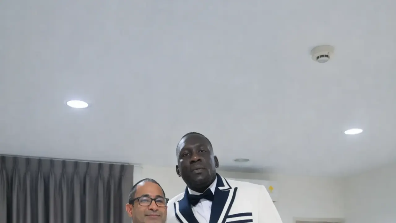 Client in a white double-breasted tuxedo jacket with navy trim standing beside a tailor
