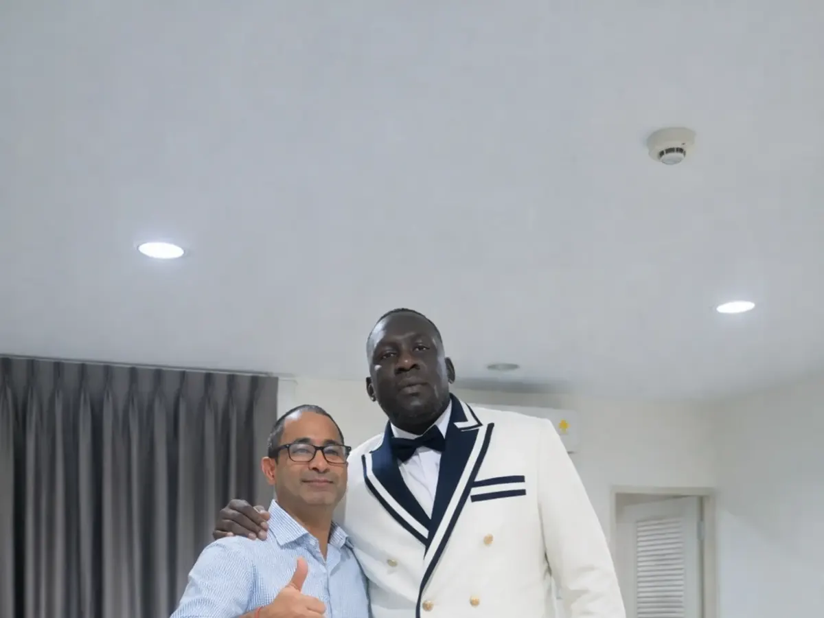 Client in a white double-breasted tuxedo jacket with navy trim standing beside a tailor