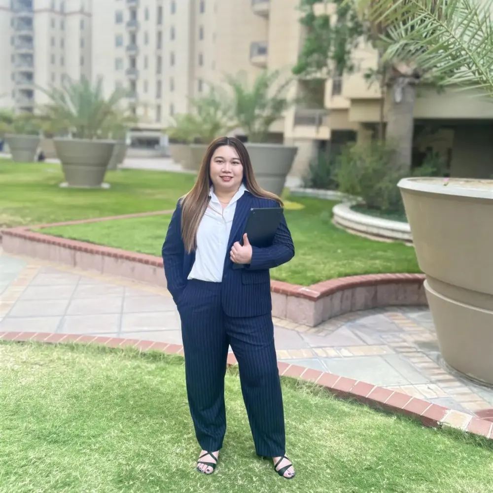 Woman in a tailored navy trouser suit standing on a lawn